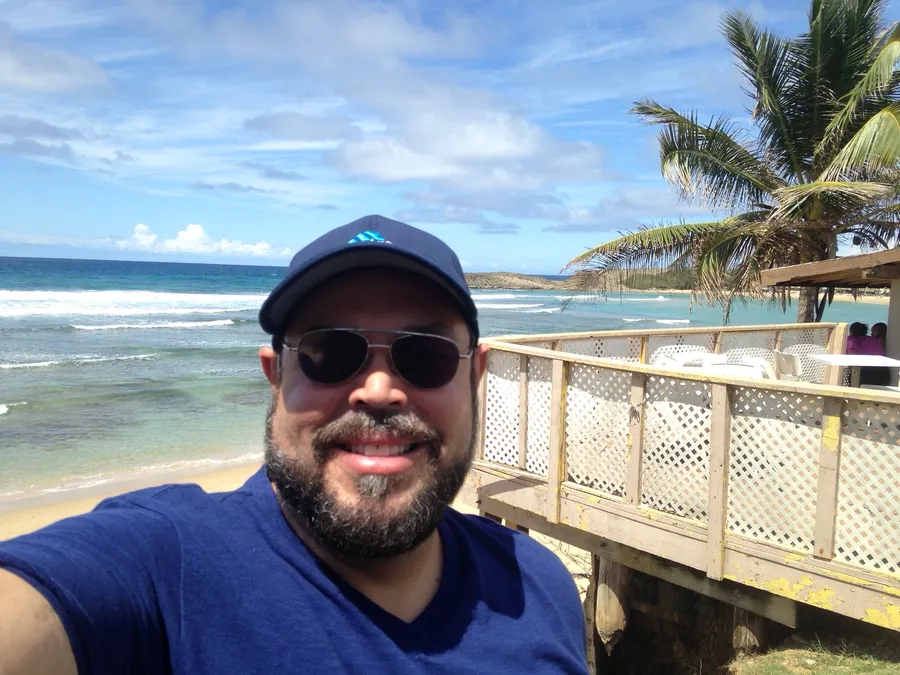 Wilfredo at the beach, palms and surf behind him